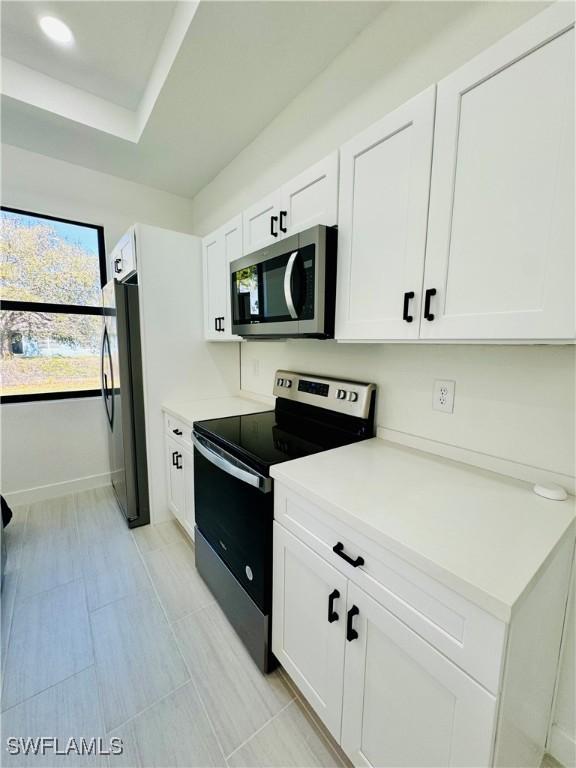 kitchen featuring stainless steel appliances, recessed lighting, light countertops, white cabinets, and baseboards