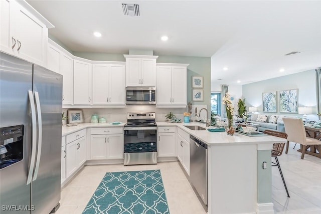 kitchen featuring visible vents, appliances with stainless steel finishes, a peninsula, light countertops, and a sink