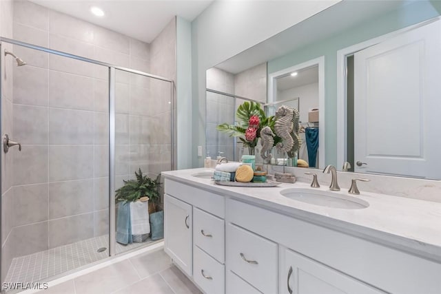 bathroom featuring double vanity, tile patterned floors, a spacious closet, a shower stall, and a sink