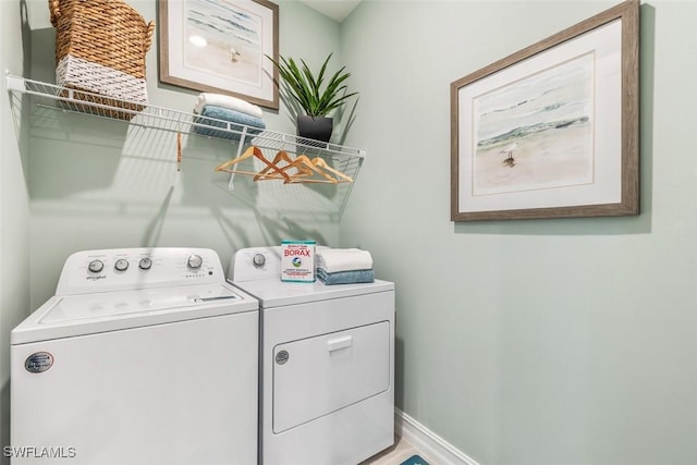 washroom featuring washing machine and dryer, laundry area, and baseboards