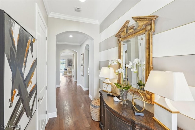 corridor with baseboards, visible vents, arched walkways, dark wood-style floors, and ornamental molding