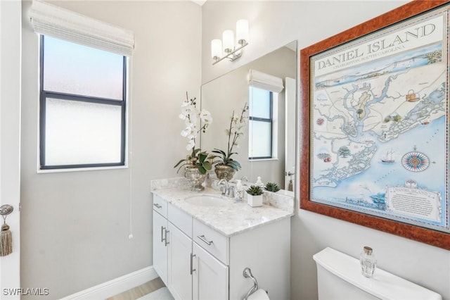 bathroom featuring toilet, baseboards, and vanity