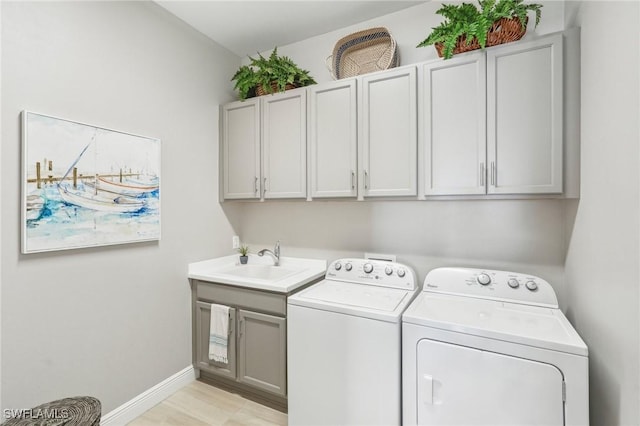 washroom featuring baseboards, cabinet space, a sink, and washing machine and clothes dryer