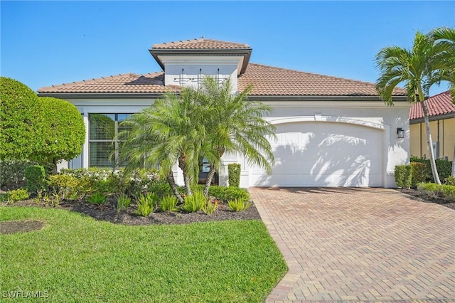 mediterranean / spanish home with a front yard, decorative driveway, a tiled roof, and an attached garage