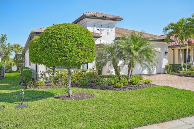 mediterranean / spanish house with a front yard, decorative driveway, and a tile roof