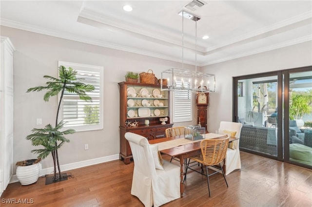 dining area featuring a tray ceiling, baseboards, visible vents, and hardwood / wood-style floors