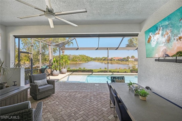 outdoor pool with ceiling fan and a water view