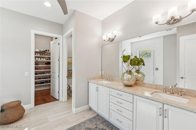 full bathroom featuring wood finished floors, a sink, baseboards, and double vanity