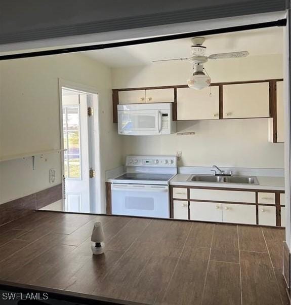 kitchen featuring white appliances, white cabinetry, a sink, and wood finished floors