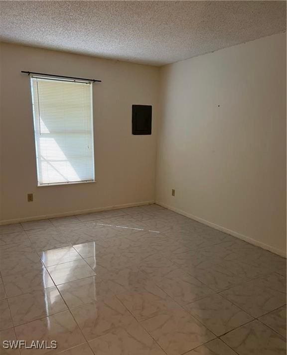 empty room featuring marble finish floor, baseboards, and a textured ceiling