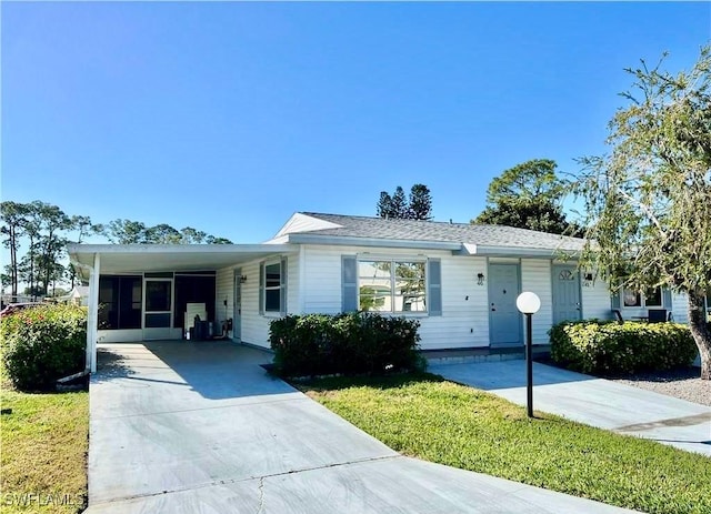 ranch-style house with a carport, driveway, and a front lawn