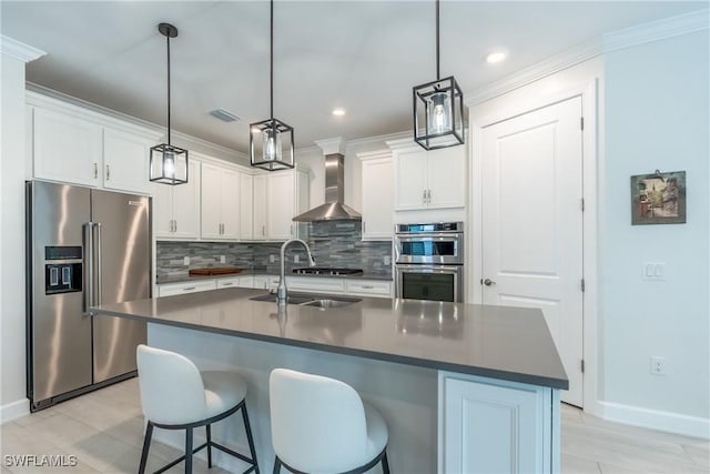 kitchen featuring white cabinets, dark countertops, appliances with stainless steel finishes, wall chimney range hood, and backsplash