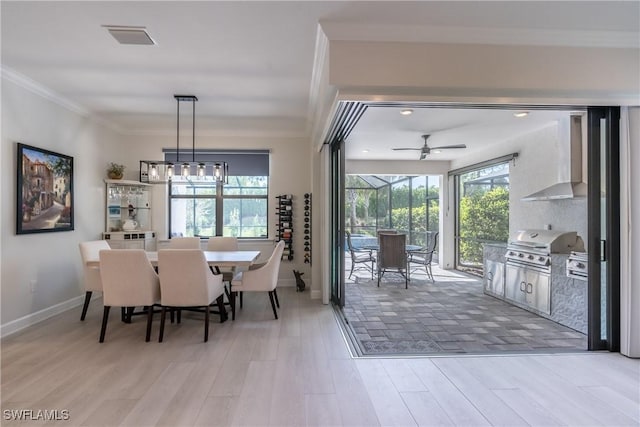 dining room with light wood finished floors, baseboards, visible vents, a sunroom, and ornamental molding