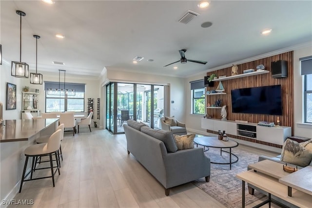 living area featuring a wealth of natural light, visible vents, and crown molding