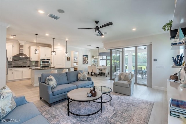 living room featuring visible vents, ornamental molding, light wood-style flooring, and baseboards