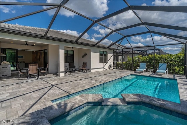 view of pool featuring a patio area, a pool with connected hot tub, glass enclosure, and a ceiling fan