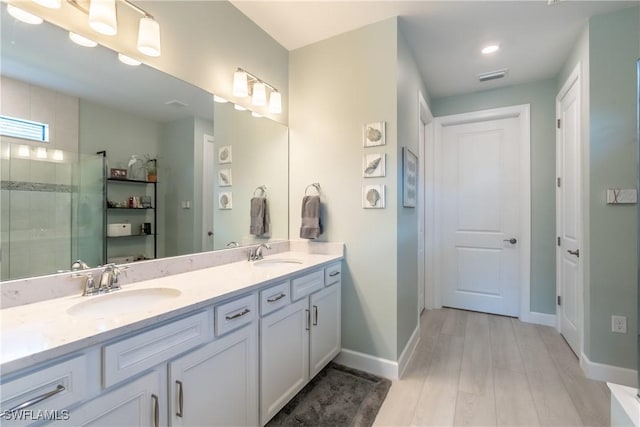 full bathroom with double vanity, visible vents, a sink, and tiled shower