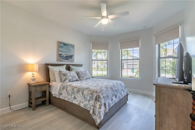 bedroom featuring light wood-style flooring, baseboards, and ceiling fan