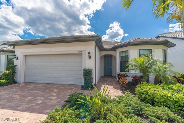 view of front of home with a garage, decorative driveway, a tile roof, and stucco siding