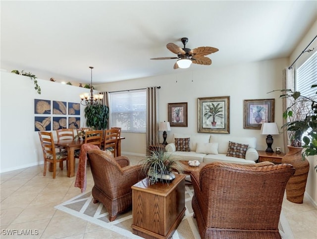 living room featuring light tile patterned flooring, baseboards, and ceiling fan with notable chandelier