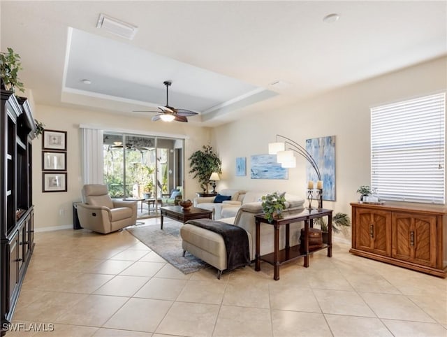 living area featuring light tile patterned flooring, a raised ceiling, visible vents, and a ceiling fan