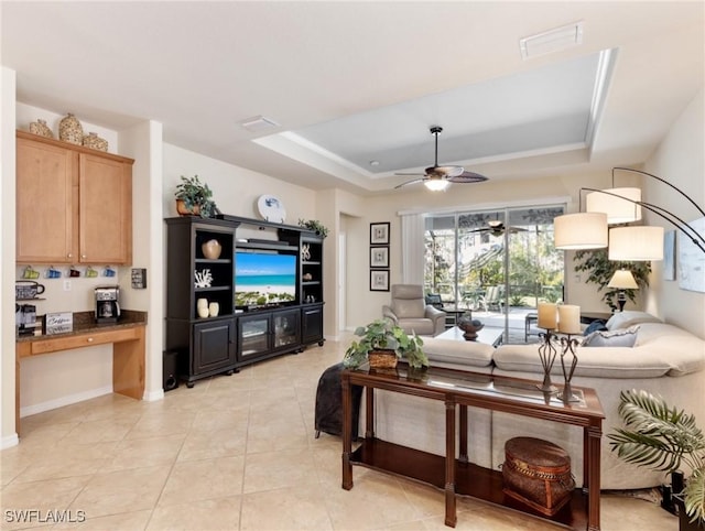 living area featuring a tray ceiling, built in desk, visible vents, a ceiling fan, and light tile patterned flooring