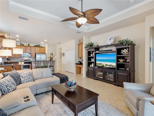 living area with light tile patterned floors, visible vents, a tray ceiling, and crown molding