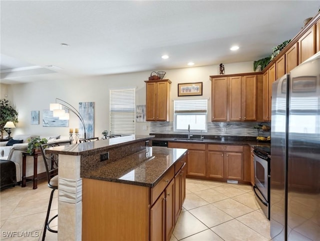 kitchen with stainless steel appliances, open floor plan, brown cabinets, and a sink