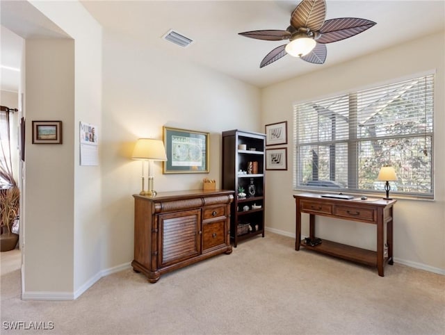 interior space with light carpet, baseboards, visible vents, and a ceiling fan