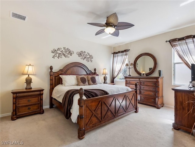 bedroom with light carpet, ceiling fan, visible vents, and baseboards