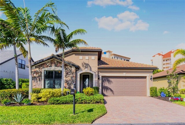 14671 Laguna Dr, Fort Myers, FL 33908 - mediterranean / spanish-style house featuring an attached garage, stone siding, decorative driveway, a tile roof, and stucco siding
