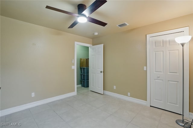 unfurnished bedroom featuring light tile patterned floors, visible vents, baseboards, and ceiling fan