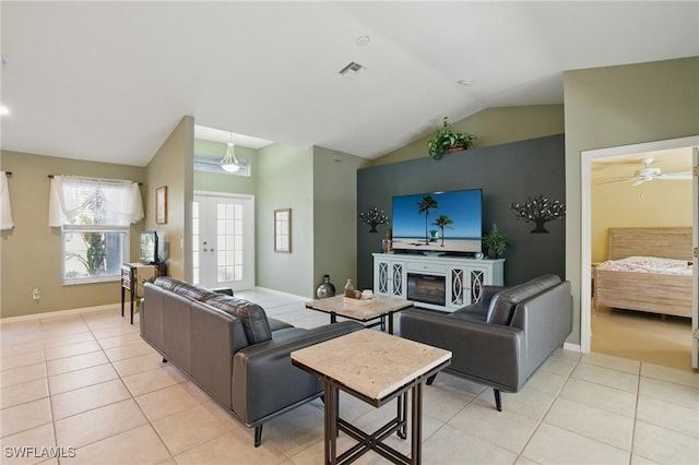 living area with visible vents, baseboards, lofted ceiling, light tile patterned floors, and a ceiling fan