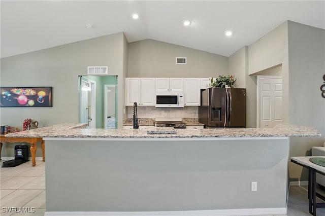 kitchen featuring visible vents, stainless steel fridge, white microwave, and white cabinetry