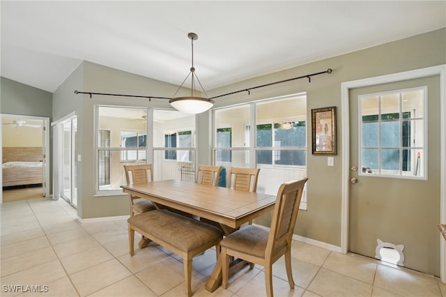 dining space with light tile patterned floors, baseboards, ceiling fan, and vaulted ceiling