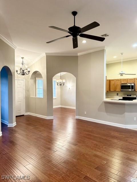 unfurnished living room featuring arched walkways, dark wood-type flooring, ornamental molding, and baseboards