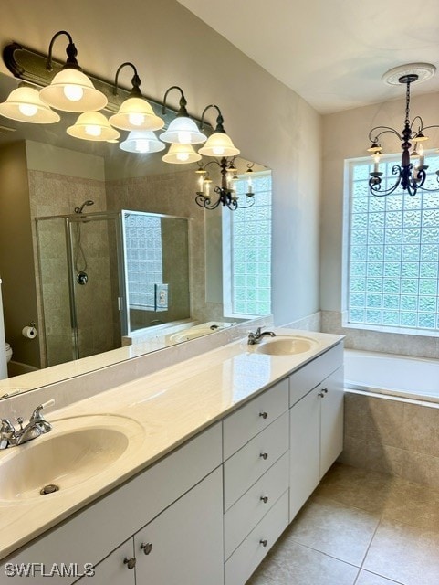 bathroom with double vanity, a shower stall, a chandelier, and a sink