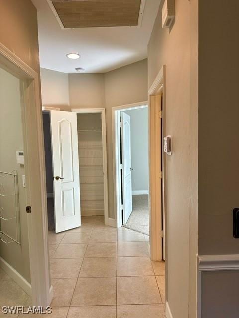 hallway with light tile patterned floors, baseboards, and visible vents