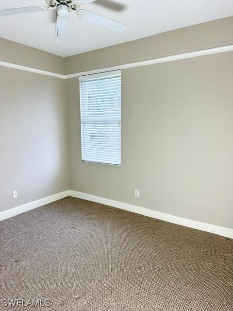 carpeted empty room with ceiling fan and baseboards