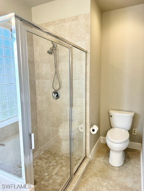 full bathroom featuring toilet, a shower stall, baseboards, and tile patterned flooring