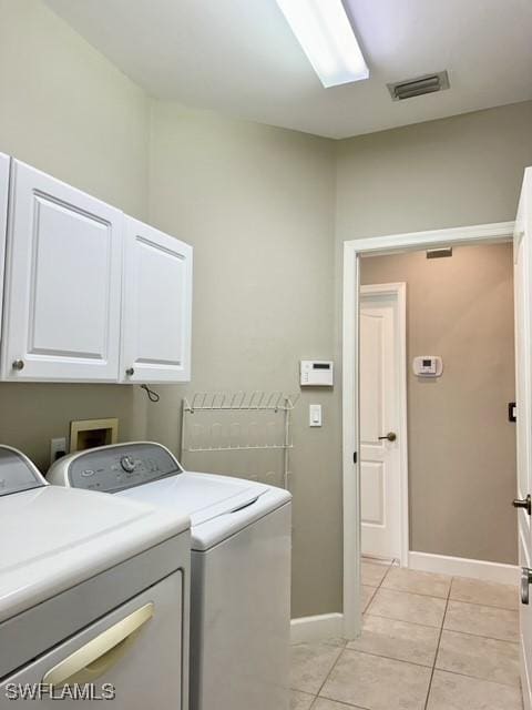 laundry room with light tile patterned floors, washing machine and dryer, visible vents, baseboards, and cabinet space