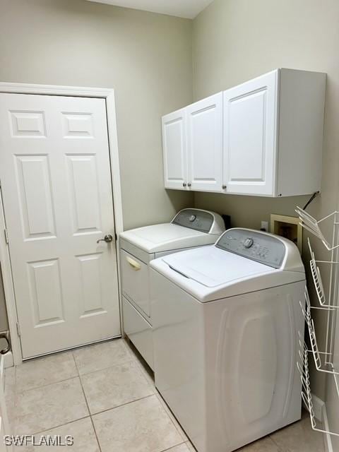 laundry area with cabinet space, light tile patterned floors, and separate washer and dryer