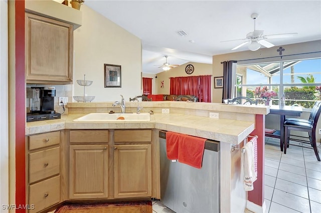 kitchen featuring light brown cabinetry, a sink, stainless steel dishwasher, a peninsula, and vaulted ceiling