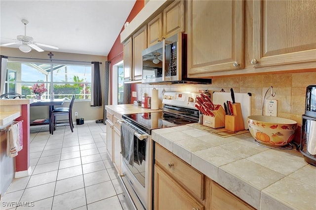 kitchen featuring stainless steel microwave, backsplash, tile counters, light tile patterned floors, and electric stove