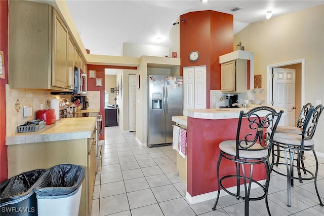 kitchen with light tile patterned floors, visible vents, a breakfast bar, a peninsula, and appliances with stainless steel finishes