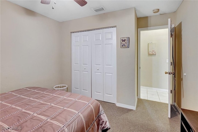 carpeted bedroom with visible vents, tile patterned floors, ceiling fan, baseboards, and a closet