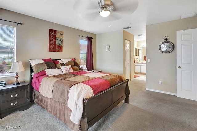 bedroom featuring visible vents, baseboards, light colored carpet, ensuite bathroom, and a ceiling fan