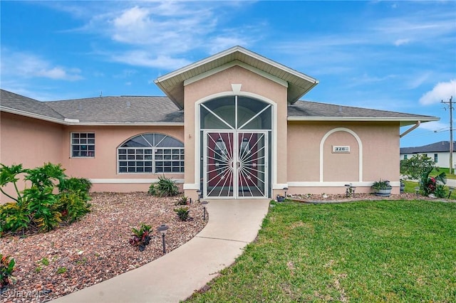 property entrance with stucco siding and a lawn