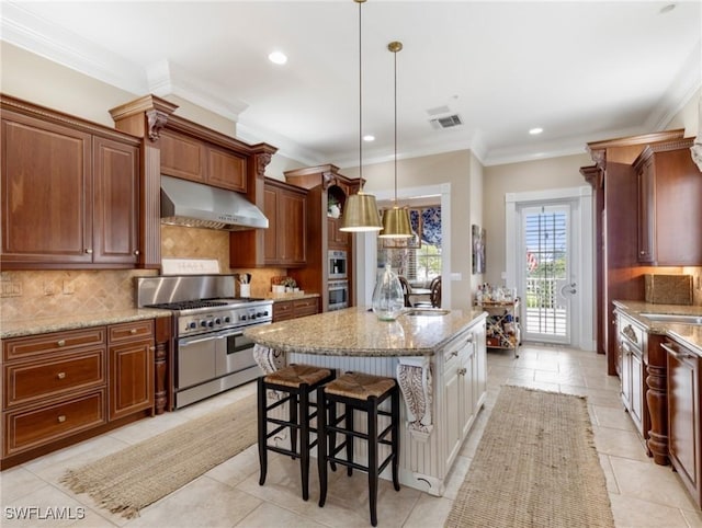 kitchen featuring light stone counters, double oven range, visible vents, an island with sink, and under cabinet range hood