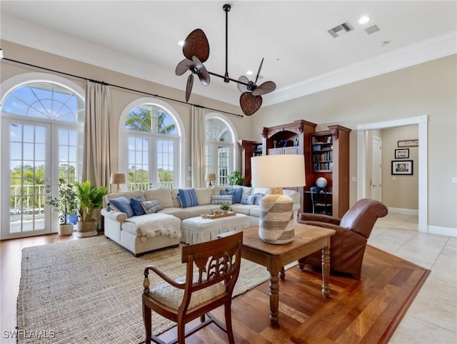 living area featuring visible vents, a notable chandelier, ornamental molding, french doors, and baseboards